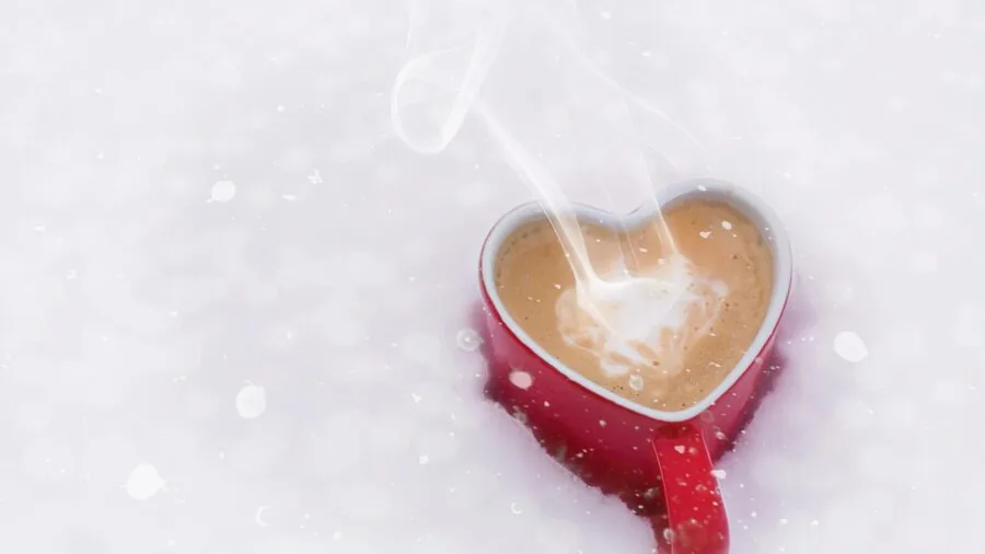Person holding warm beverage during outdoor morning commute with steam visible from cup