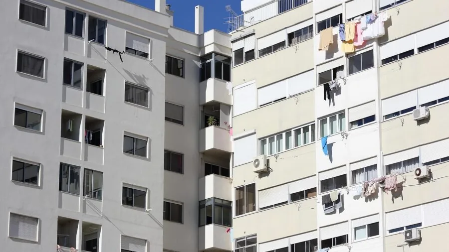 Person in apartment laundry room folding clothes from washer dryer combo