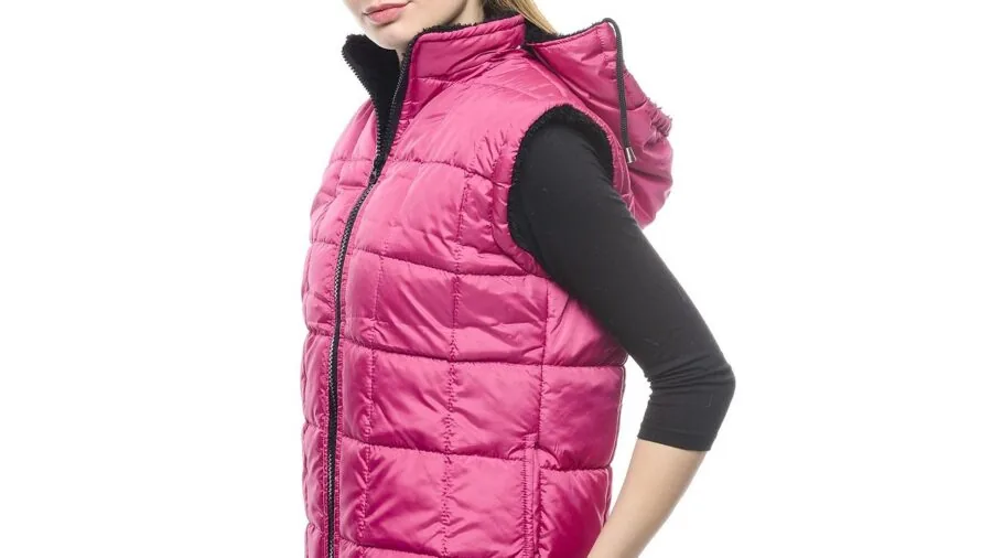 Person in blaze orange vest layered over heavy jacket in outdoor hunting setting