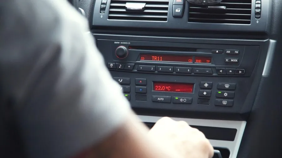 Person in car adjusting FM radio dial on dashboard while driving