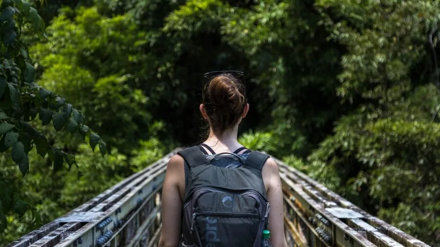 Person in outdoor setting adjusting backpack frame and load transfer system while hiking
