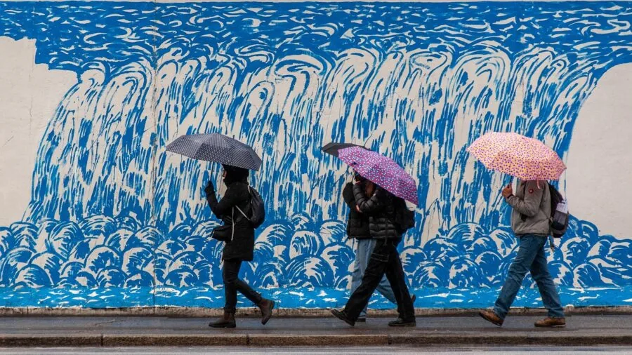 Person in winter clothing walking through snowy wet terrain during cold rainy weather