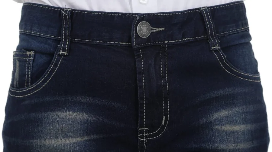 Person in worn jeans doing laundry, showing natural fabric fading and texture from washing