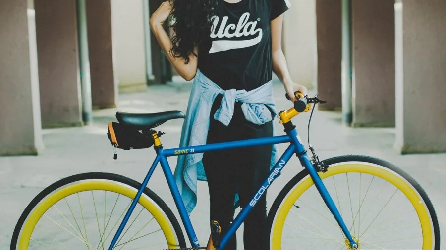 Person inspecting bicycle wheel and frame in outdoor setting to verify compatibility