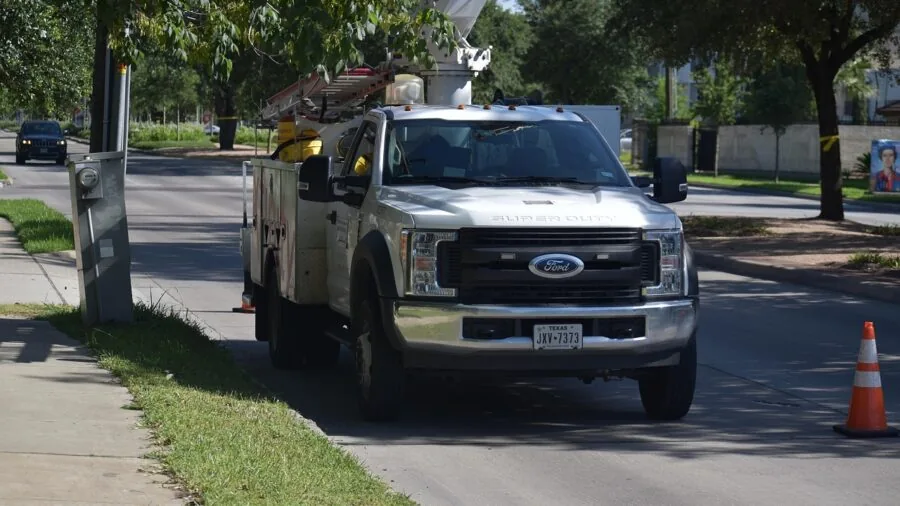 Person inspecting heavy-duty truck equipment in outdoor industrial setting during maintenance work