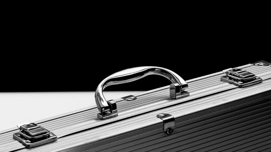 Person inspecting suitcase lock before airport travel, focused on TSA security features