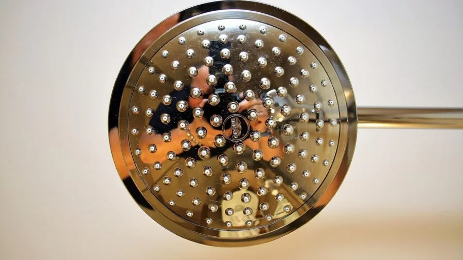 Person installing a new shower head in a modern bathroom, demonstrating the simple DIY installation process