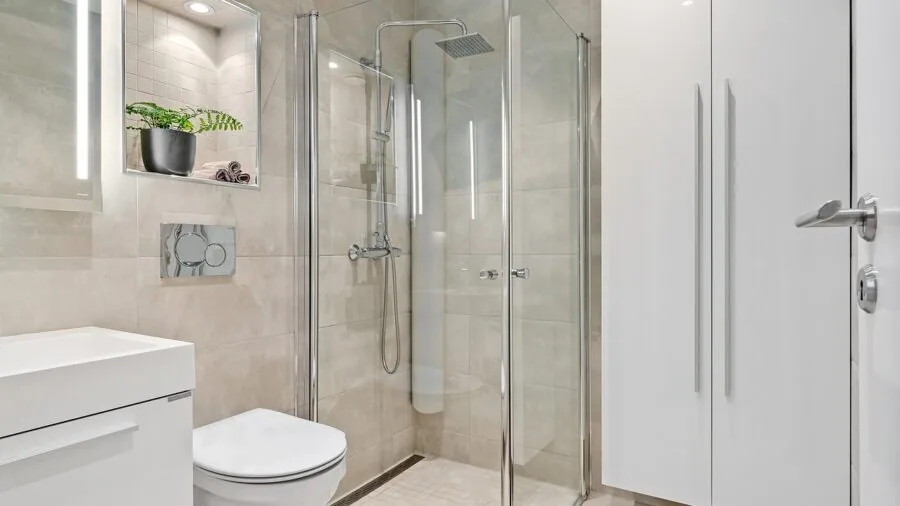 Person installing shower fixture on bathroom wall with tools and materials visible