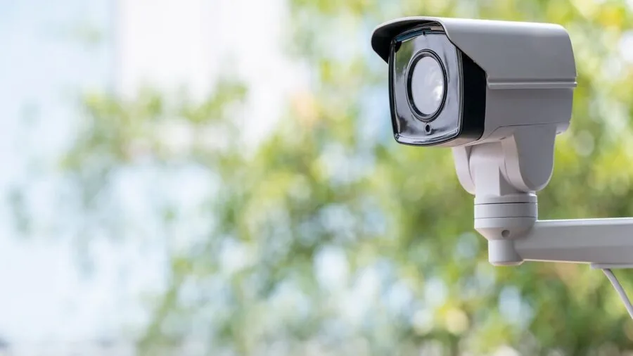 Person installing weatherproof security camera on residential home exterior in daylight
