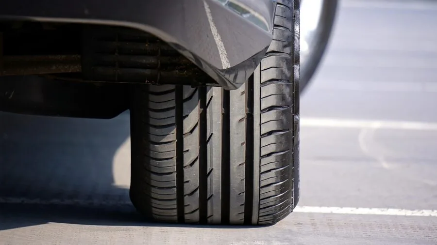 Person installing wheel chocks under large vehicle tire for parking lot safety