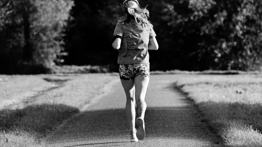Person jogging outdoors on a sunny day, showing active fitness lifestyle and cardio exercise routine