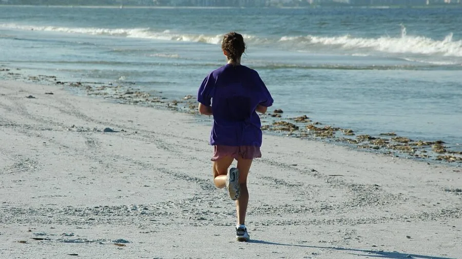 Person jogging outdoors on a sunny path, demonstrating active running lifestyle and fitness routine
