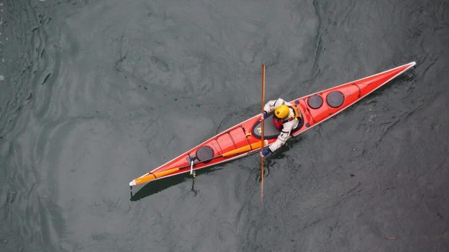 Person kayaking on calm water with gear, demonstrating water safety and outdoor paddling adventure