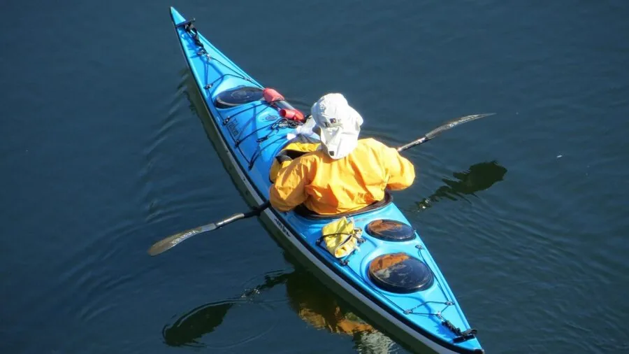 Person kayaking on water with paddle in dynamic outdoor setting