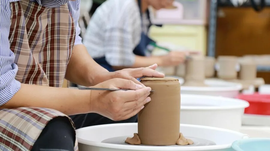 Person learning a new craft skill with instructional guidance and materials on a table