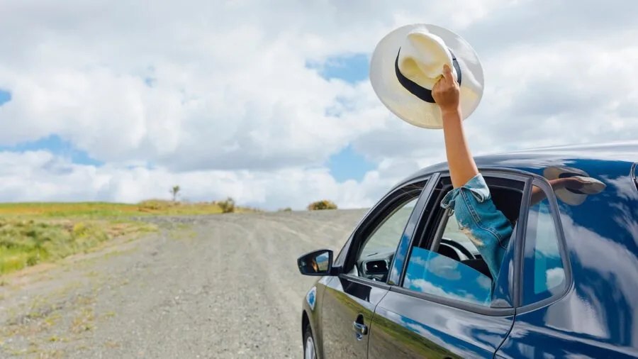 Person loading camping gear onto vehicle roof rack for road trip adventure