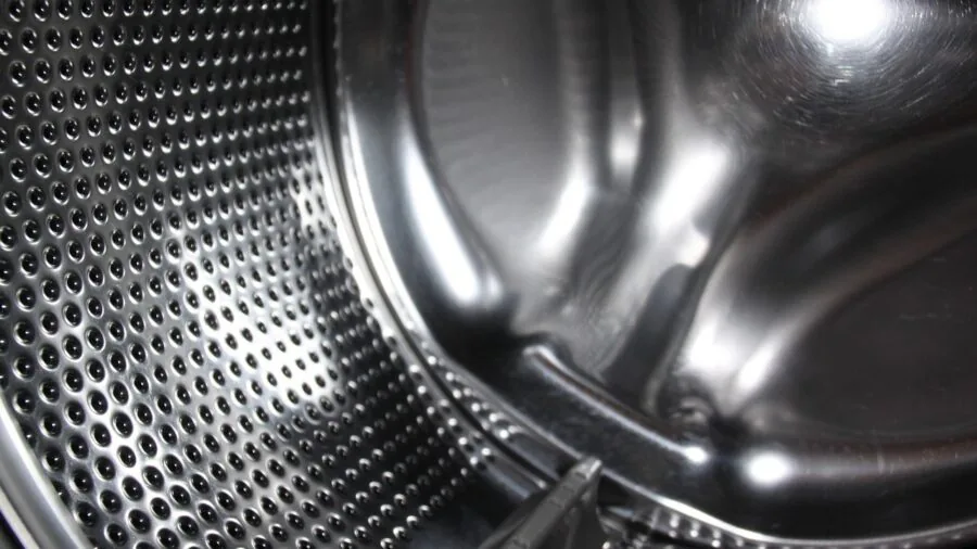 Person loading clean dishes into an open dishwasher in a bright, modern kitchen