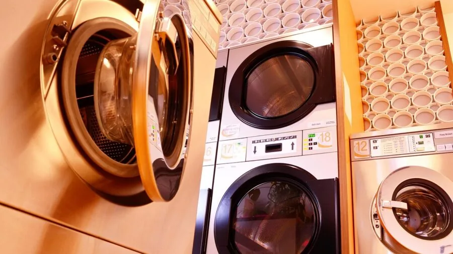 Person loading colorful fabrics into washing machine for cleaning