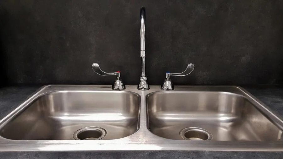 Person loading stainless steel kitchenware into a modern dishwasher in a bright home kitchen