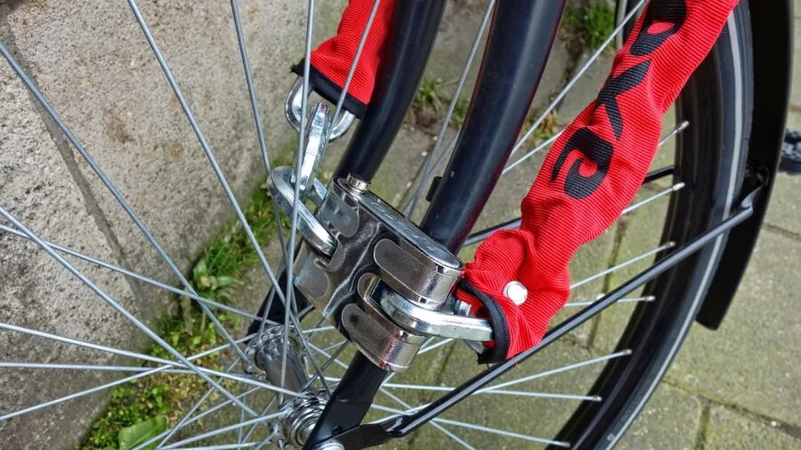 Person locking up bicycle outdoors with chain lock, secure parking scene
