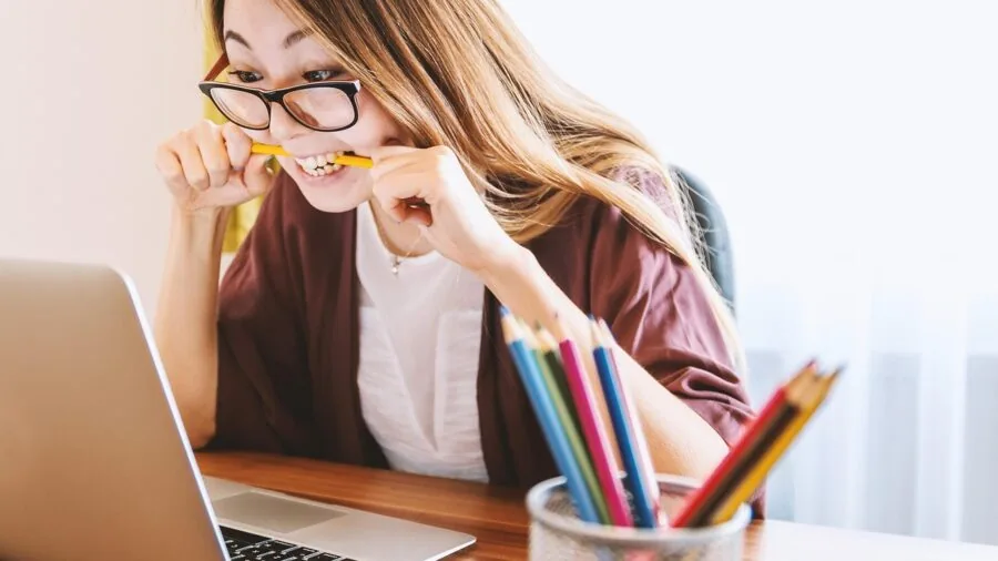Person looking frustrated while working on a slow laptop computer at desk