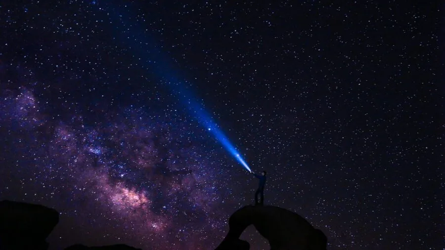 Person looking through telescope at night observing stars and constellations