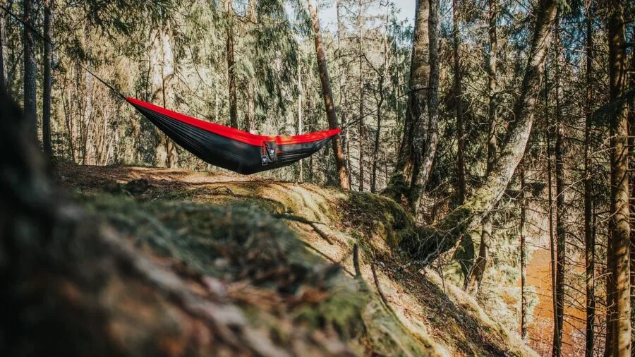 Person lying diagonally in a camping hammock suspended between trees in nature
