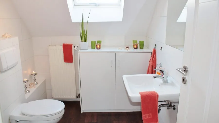 Person measuring bathroom toilet space with tape measure for storage planning