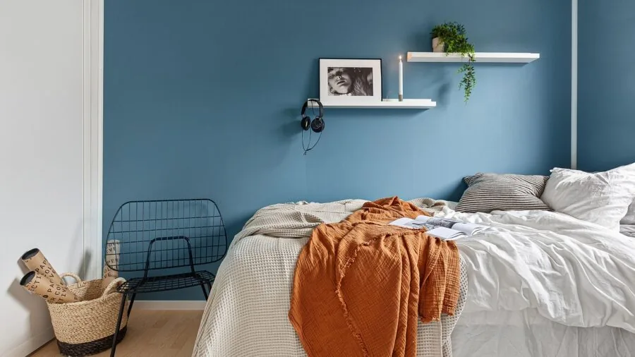 Person measuring bed frame dimensions with tape measure in modern bedroom