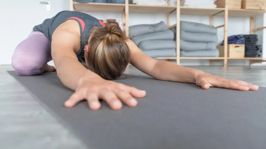 Person measuring rolled yoga mat dimensions with tape measure for proper bag fit