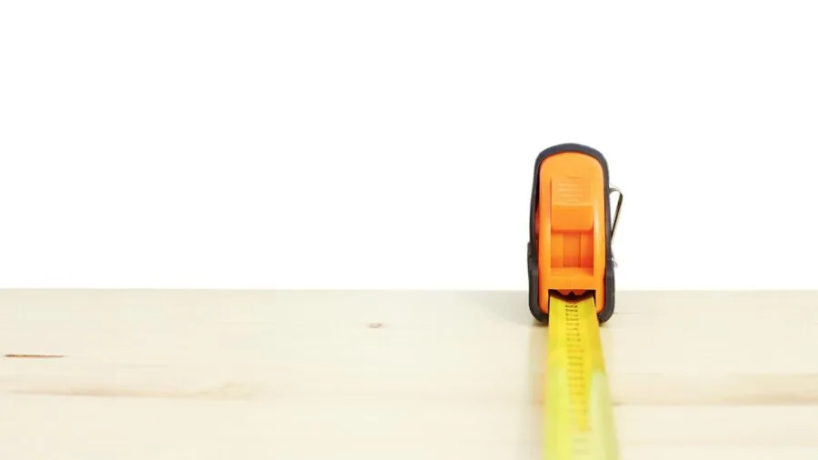 Person measuring wall length with tape measure during home renovation project
