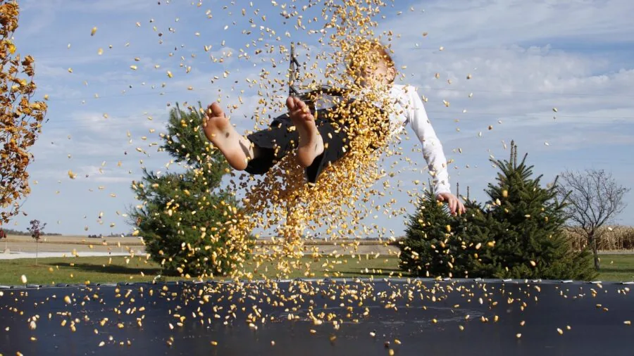 Person mid-bounce on trampoline in backyard during daytime exercise session