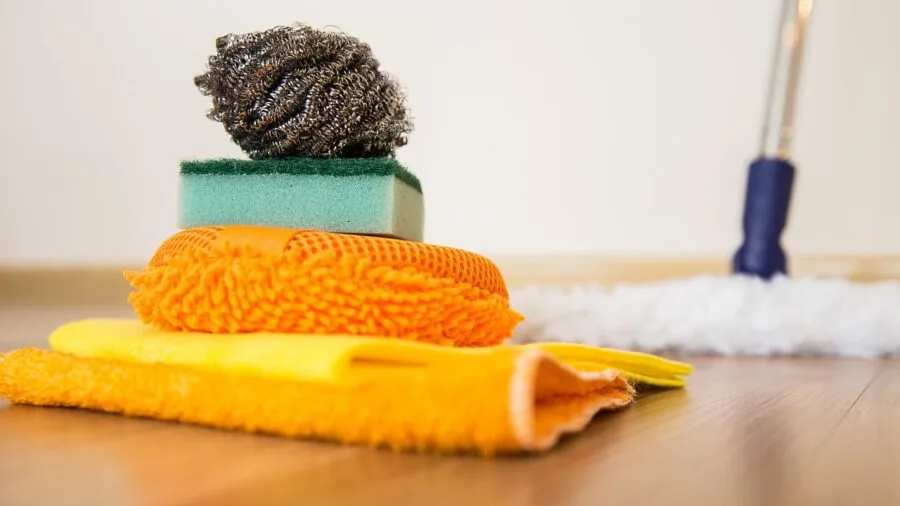 Person mopping hardwood floor with water and cloth in bright home interior