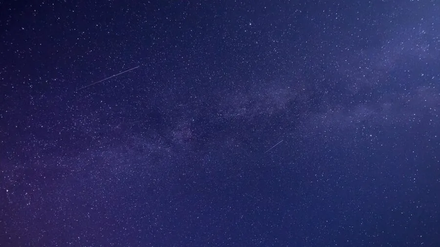 Person observing the night sky through a telescope under stars