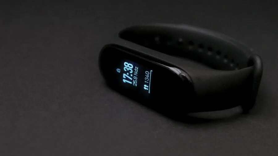 Person on exercise bike monitoring workout metrics on wrist display during indoor training session