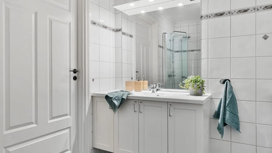 Person opening bathroom cabinet door in modern bathroom with adequate clearance space