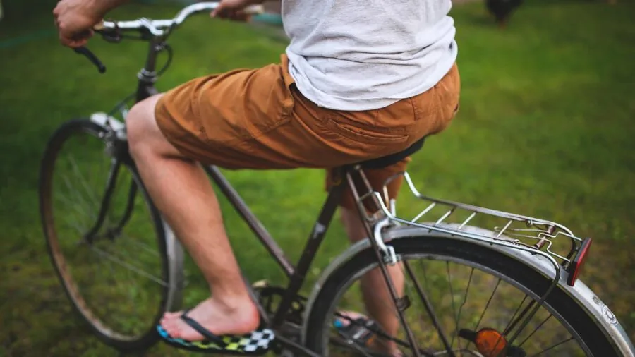 Person opening car trunk while bikes are mounted on rear rack tilted away from vehicle