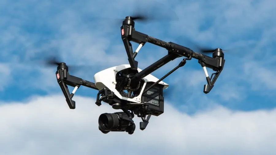 Person operating a drone in an open outdoor field with clear sky