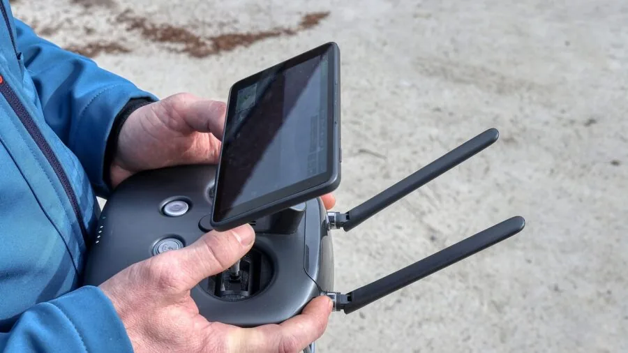 Person operating drone outdoors with remote controller during golden hour flight