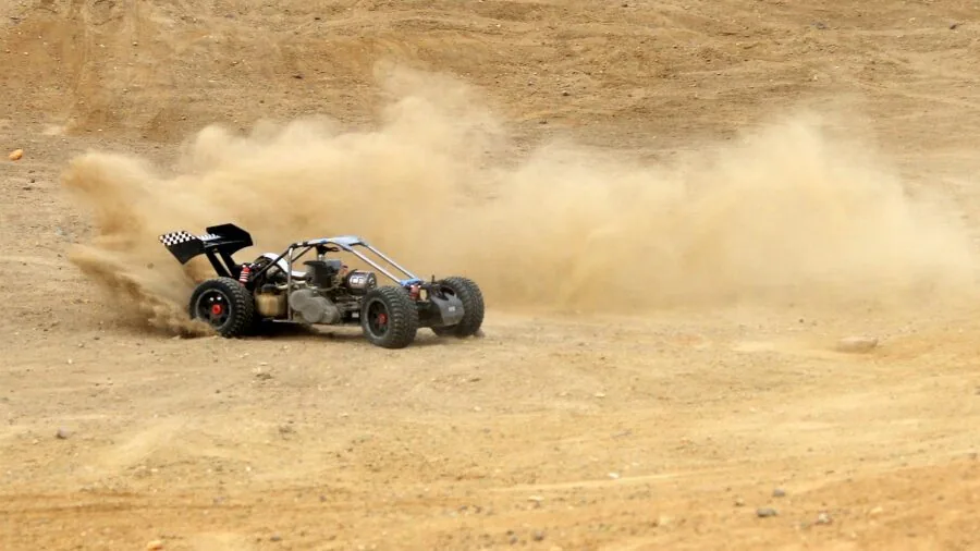 Person operating RC car on outdoor track with focus and concentration during competitive racing session