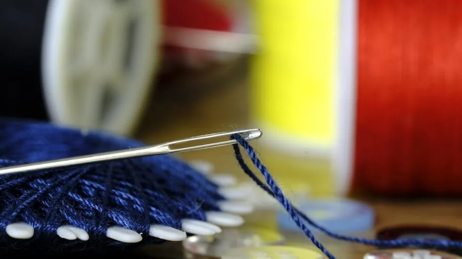 Person organizing and curating sewing supplies at a wooden desk workspace