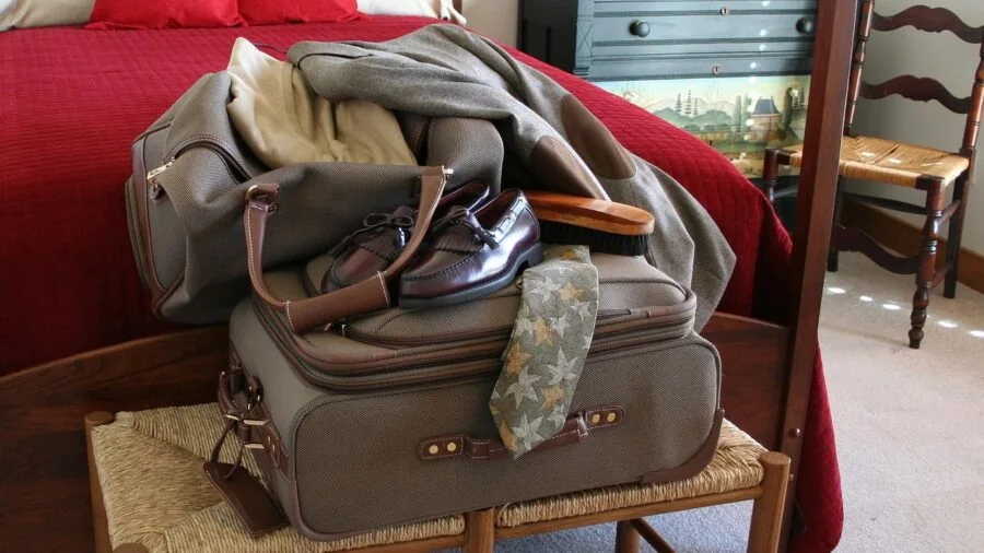 Person organizing and packing clothes efficiently into an open suitcase with compartments