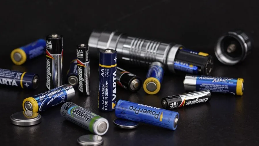 Person organizing and storing rechargeable batteries in a home workspace with care and attention to detail