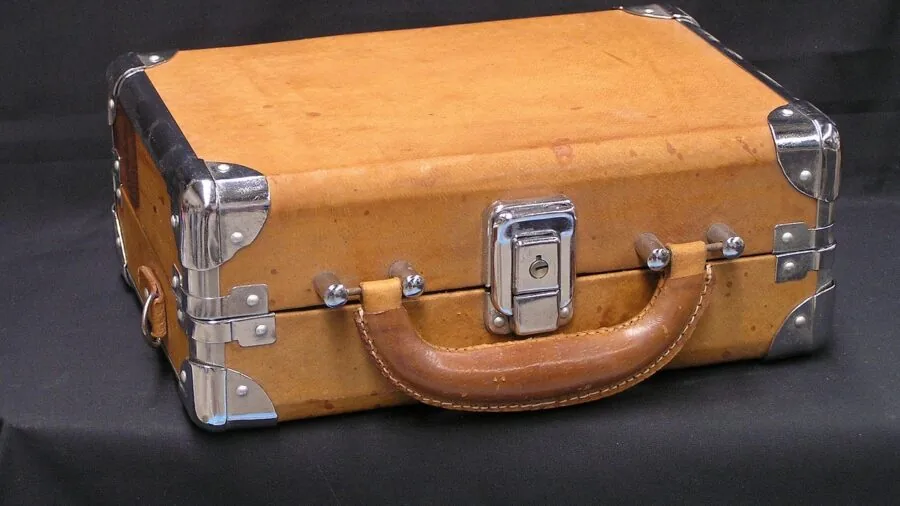 Person organizing board game pieces into a wooden carrying case at home table
