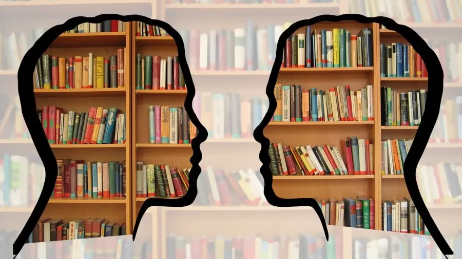 Person organizing books on wooden shelf with adjustable dividers and bookends in home study space
