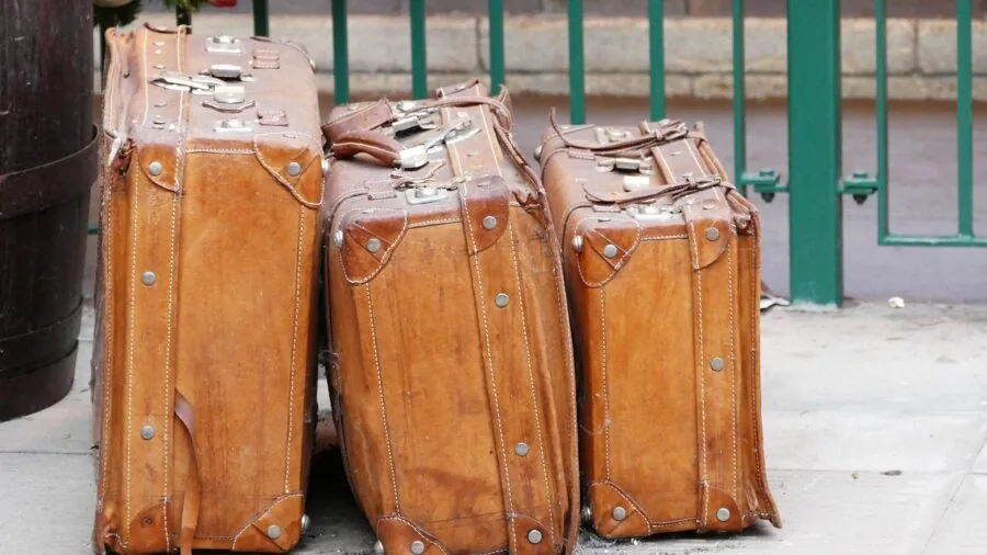 Person organizing clothes and items into luggage while preparing for travel, showing real packing scenario