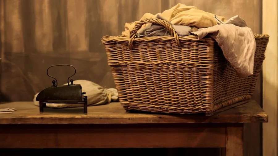 Person organizing clothes in a single laundry basket in a bedroom setting