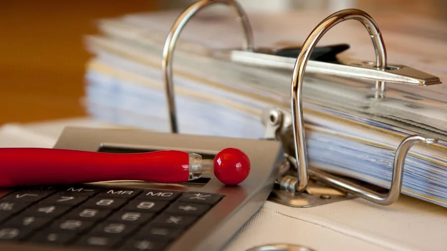 Person organizing important documents and papers into labeled folders and compartments on a desk
