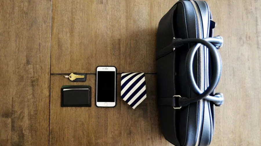 Person organizing personal items including wallet, keys, and bag on wooden surface