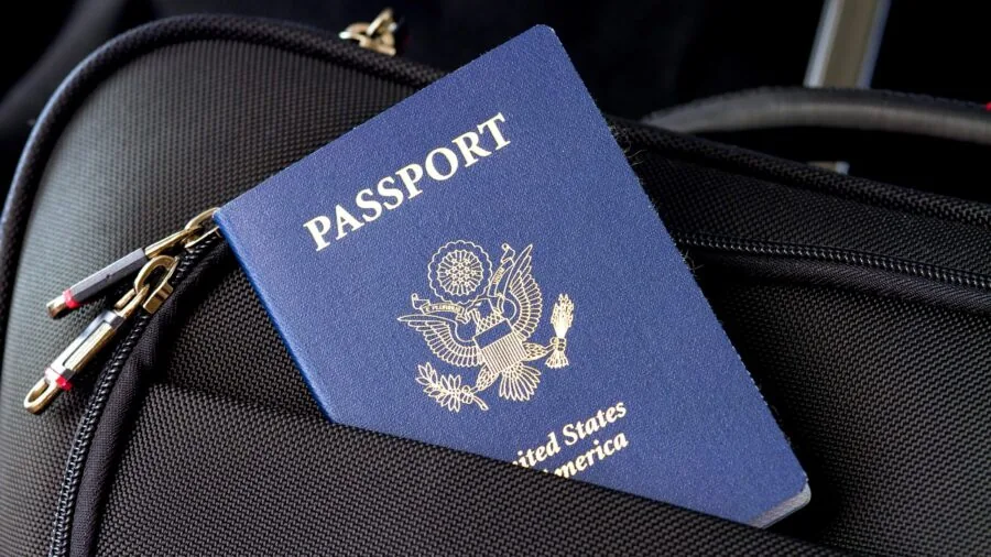 Person organizing travel documents and passport in luggage while preparing for trip